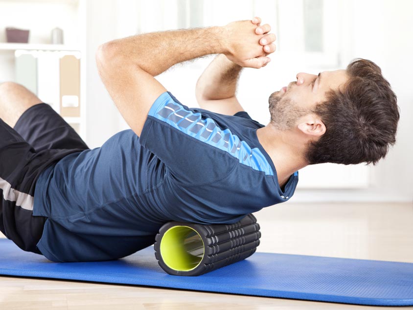A man rolls his back on a foam roller